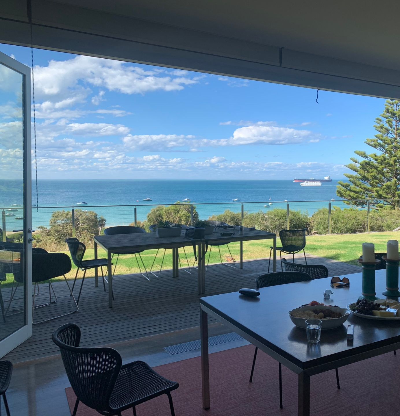 Covered patio with table and chairs overlooking a sunny ocean view and blue sky — KM Custom Homes In Mount Eliza, VIC