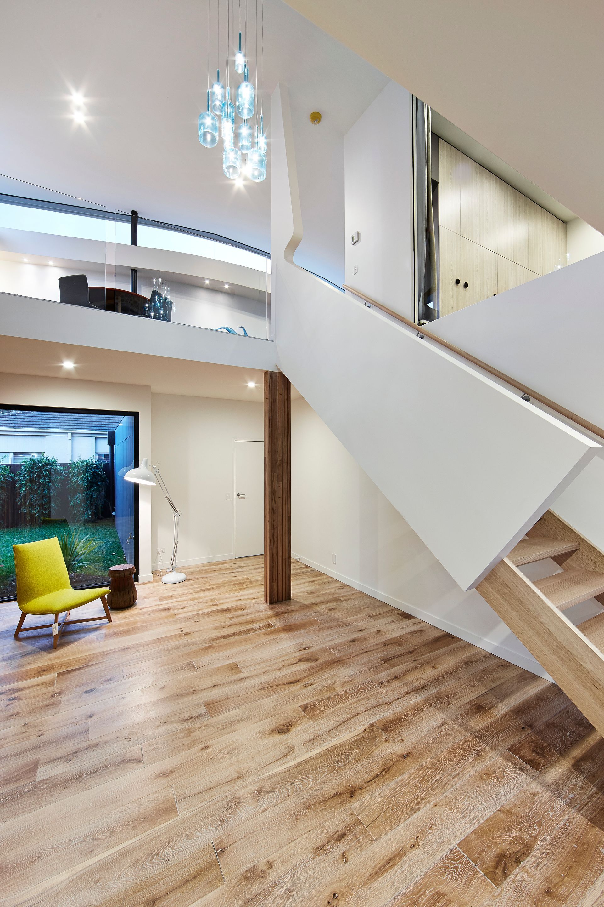 A Living Room With A Staircase And A Yellow Chair — KM Custom Homes In Mount Eliza, VIC