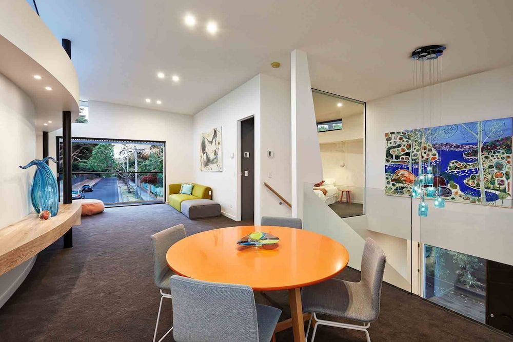 A Dining Room With A Round Orange Table And Chairs — KM Custom Homes In Mount Eliza, VIC