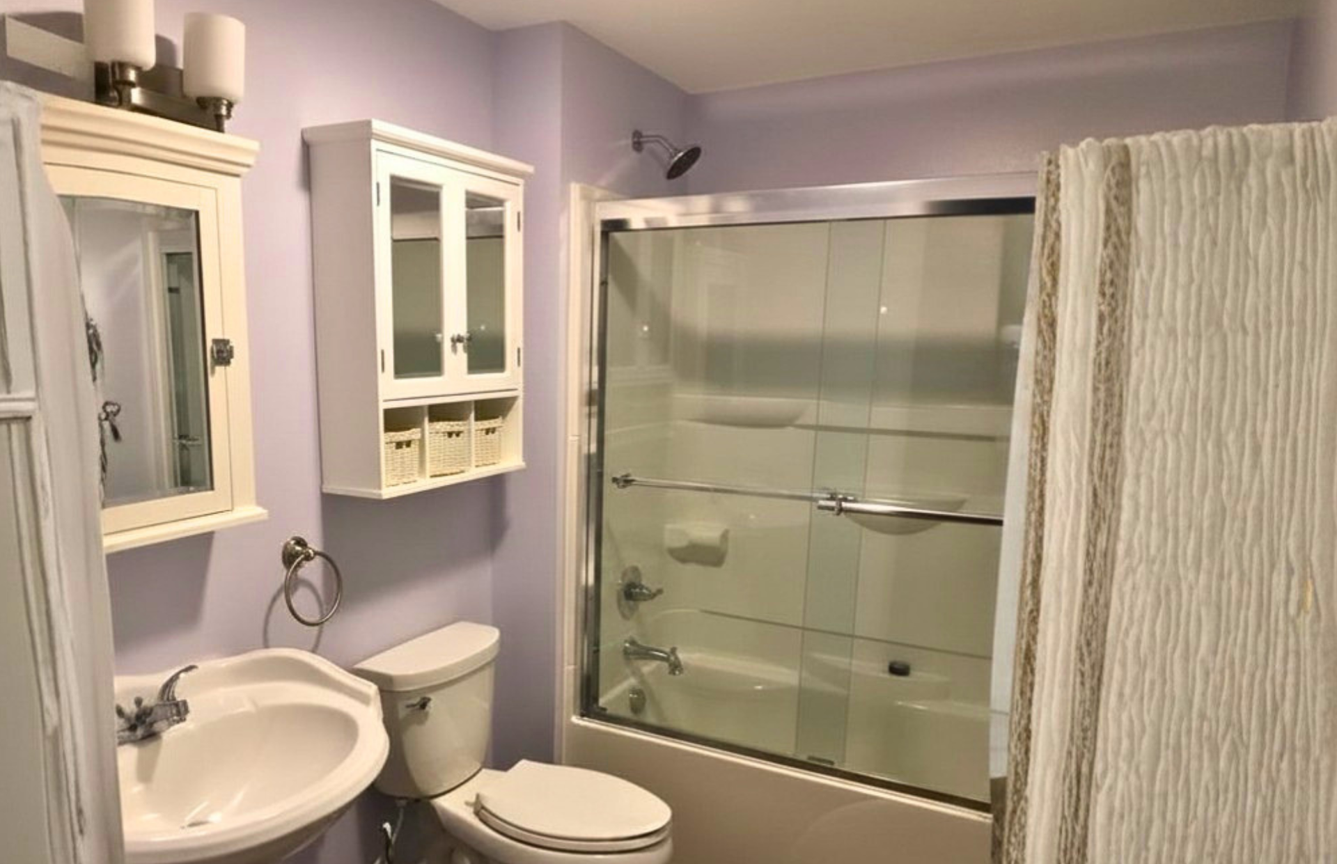 Lavender bathroom with sink, toilet, glass shower, mirror cabinets, and white shower curtain
