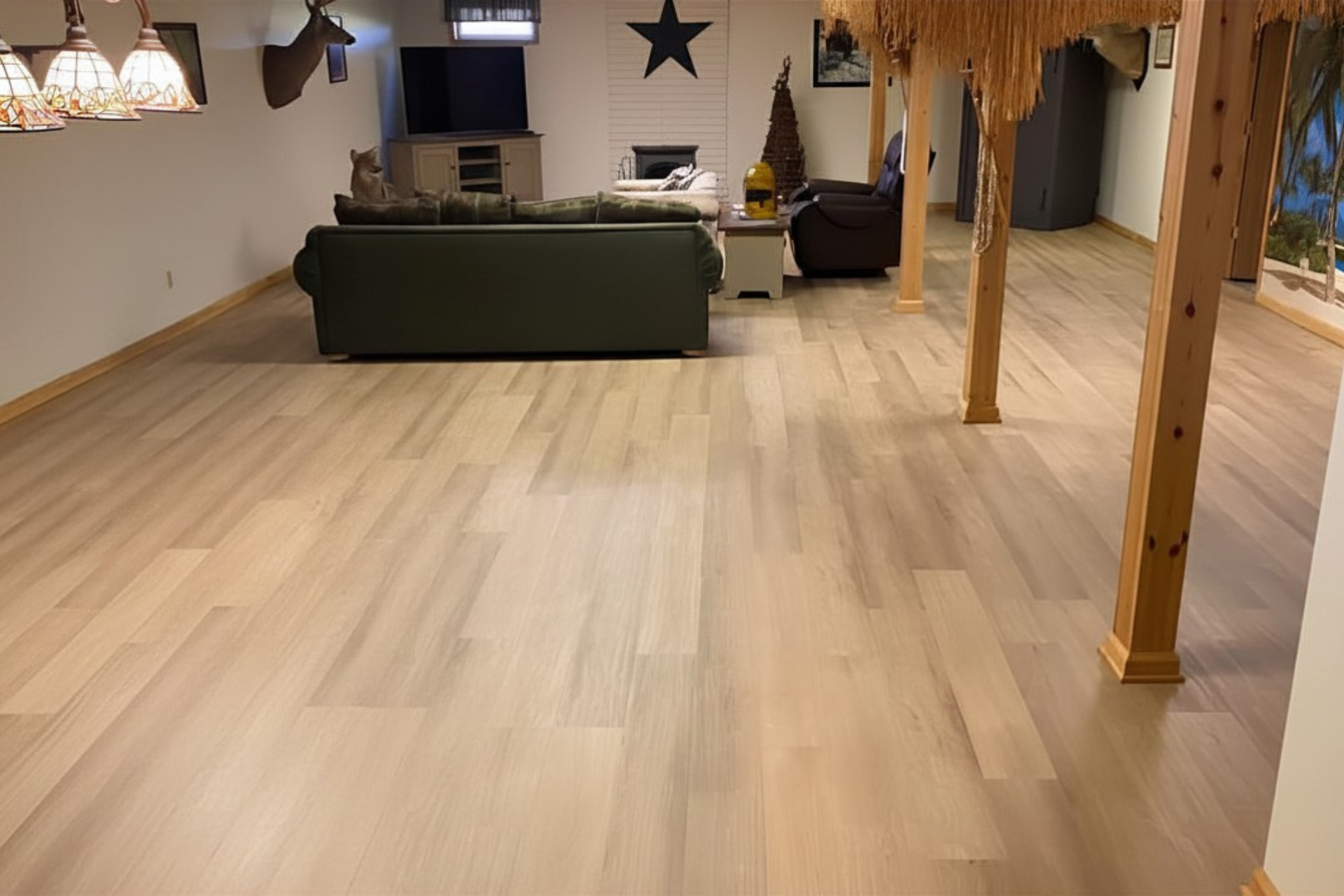 Spacious living room with light wood floors, dark sofa, hanging star decor, and wooden support beams