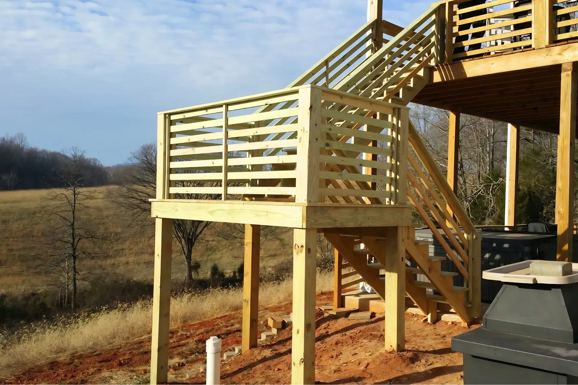 Wooden elevated deck with stairs and railing on a hillside under construction