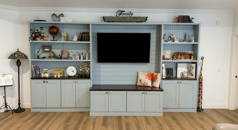 Built-in living room wall unit with TV, light blue cabinets, and decorative shelves