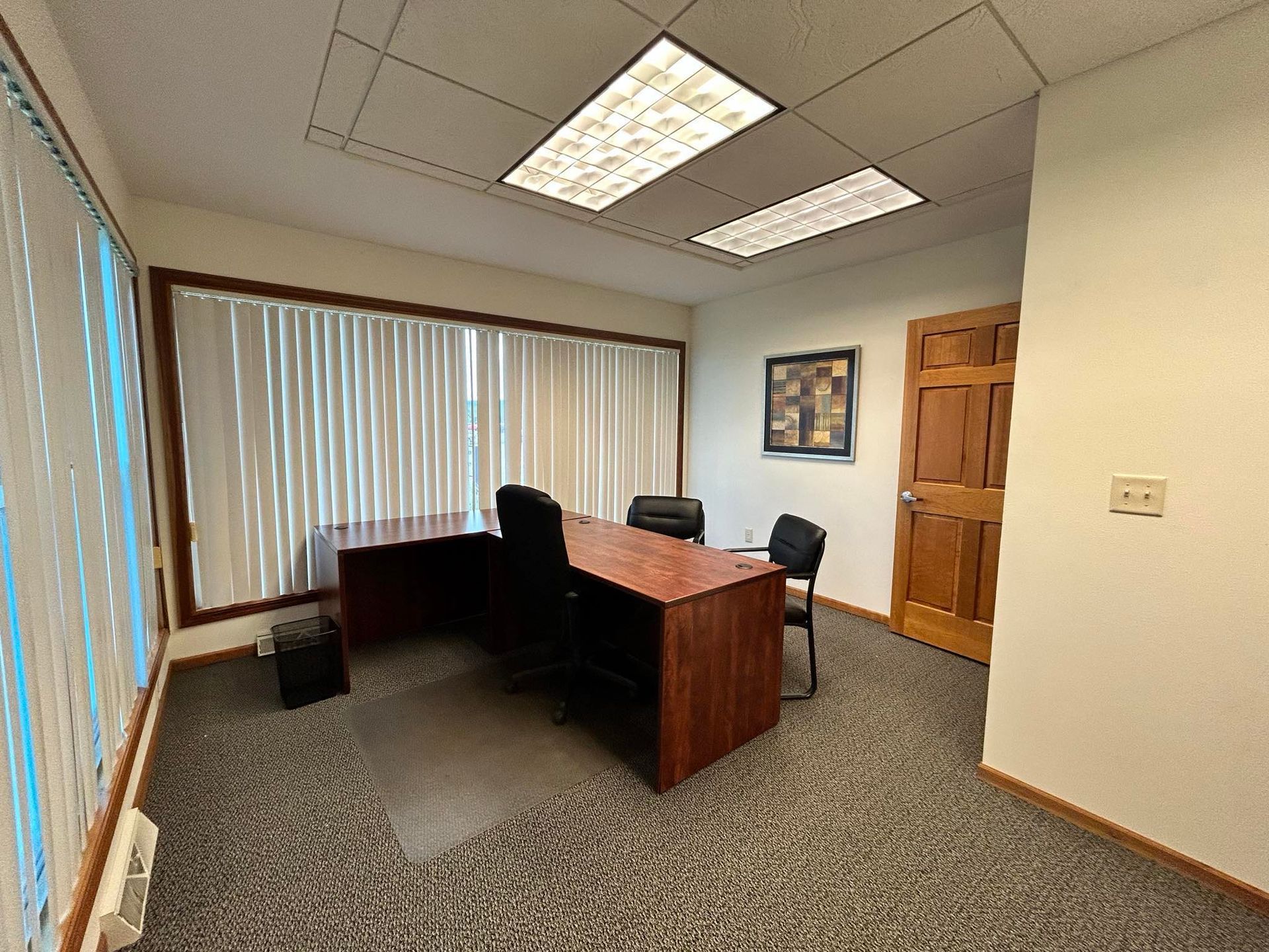 A small office with a desk and chairs in it.