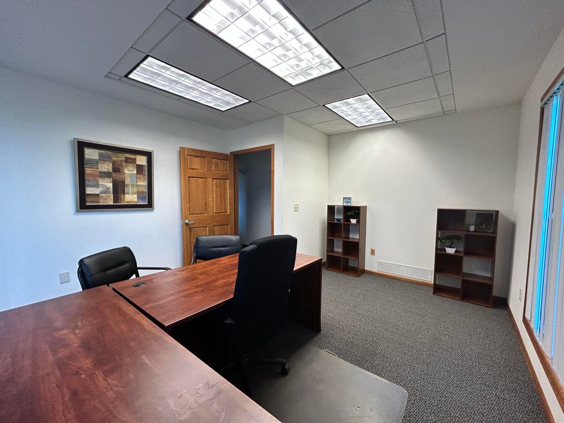 A small office with a wooden desk and chairs