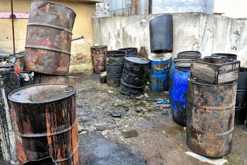 A bunch of barrels are stacked on top of each other in a yard.