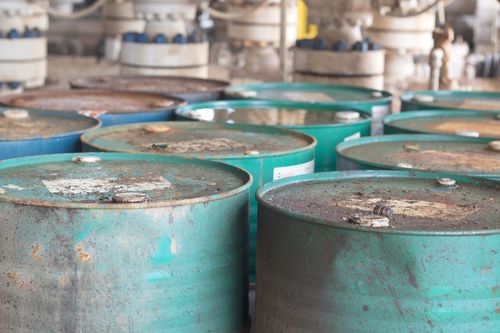 A bunch of green barrels are stacked on top of each other in a room.