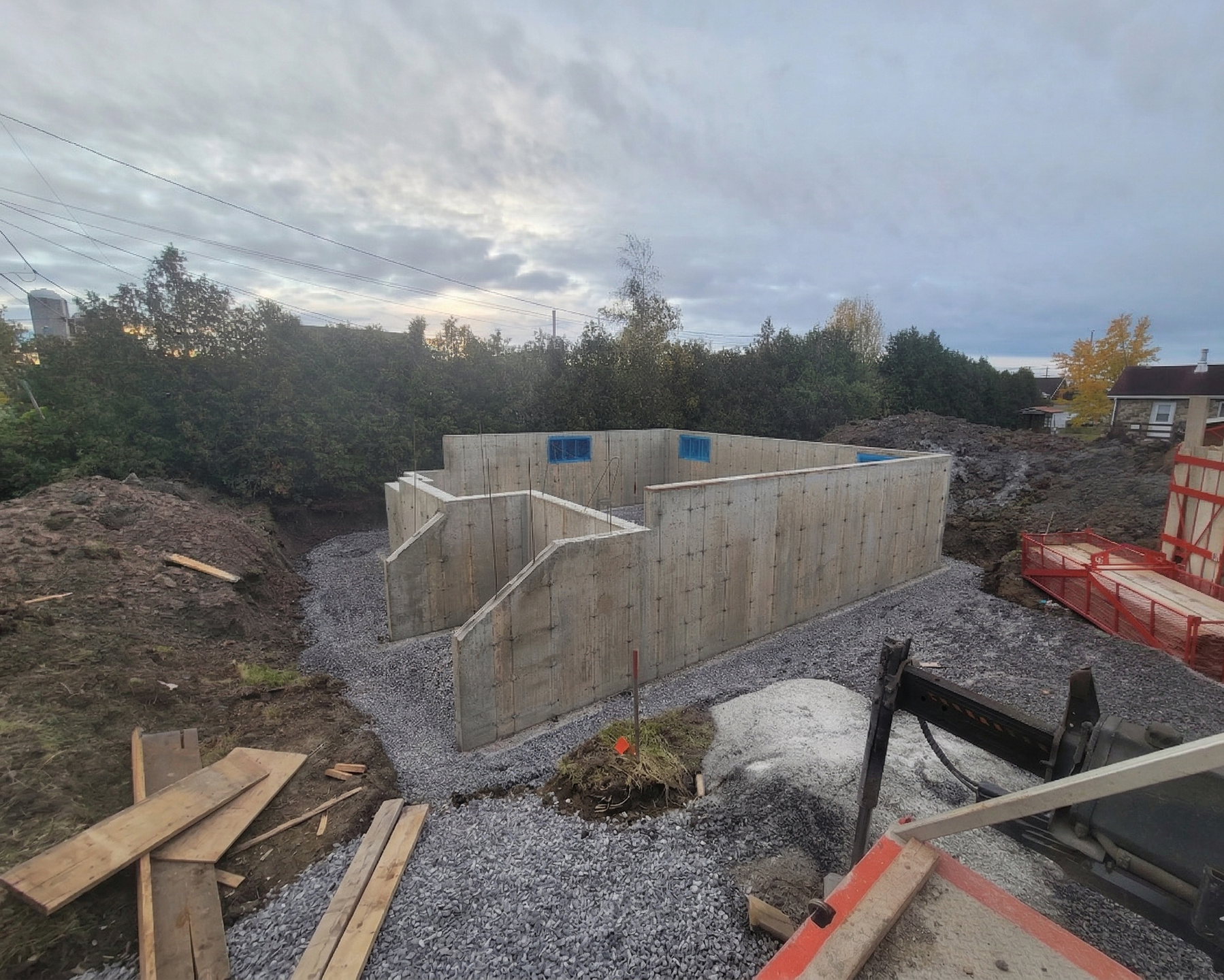 Fondations en béton partiellement construites sur un chantier de gravier au crépuscule
