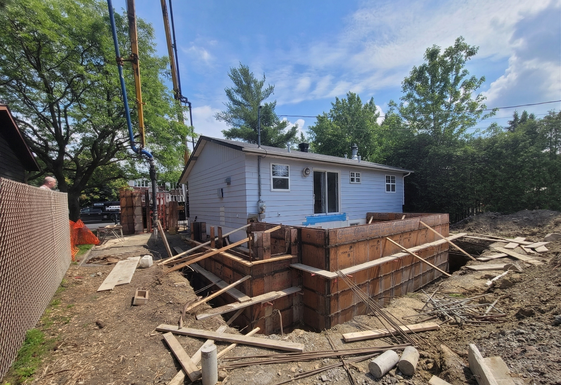 Maison en construction avec fouilles de fondation, charpente en bois et tas de terre à l'extérieur
