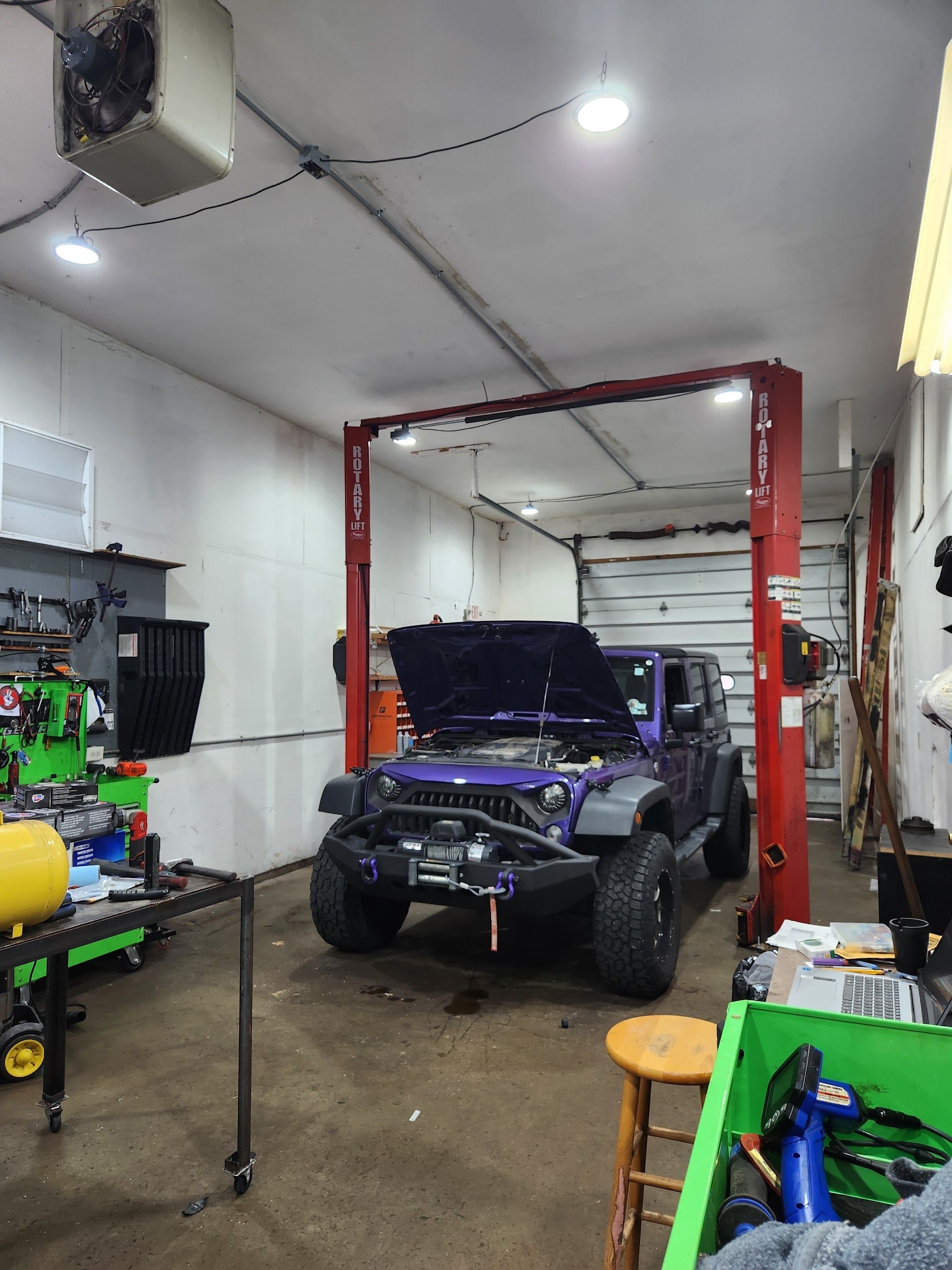 Blue SUV with open hood in an auto shop bay, surrounded by tools and equipment. | Oak Auto