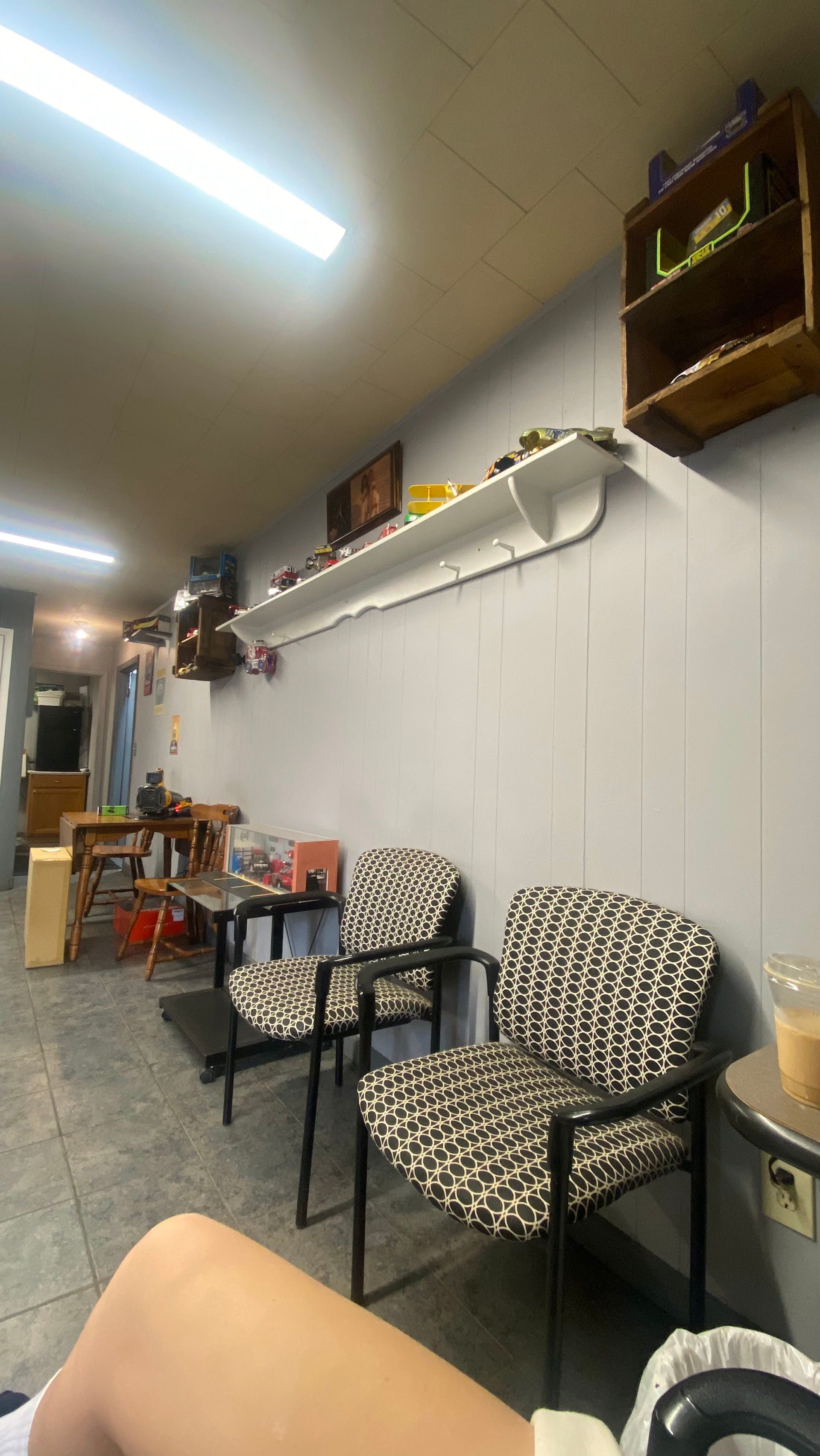 Small waiting area with patterned chairs, shelves, and white wall panels under fluorescent lighting | Oak Auto