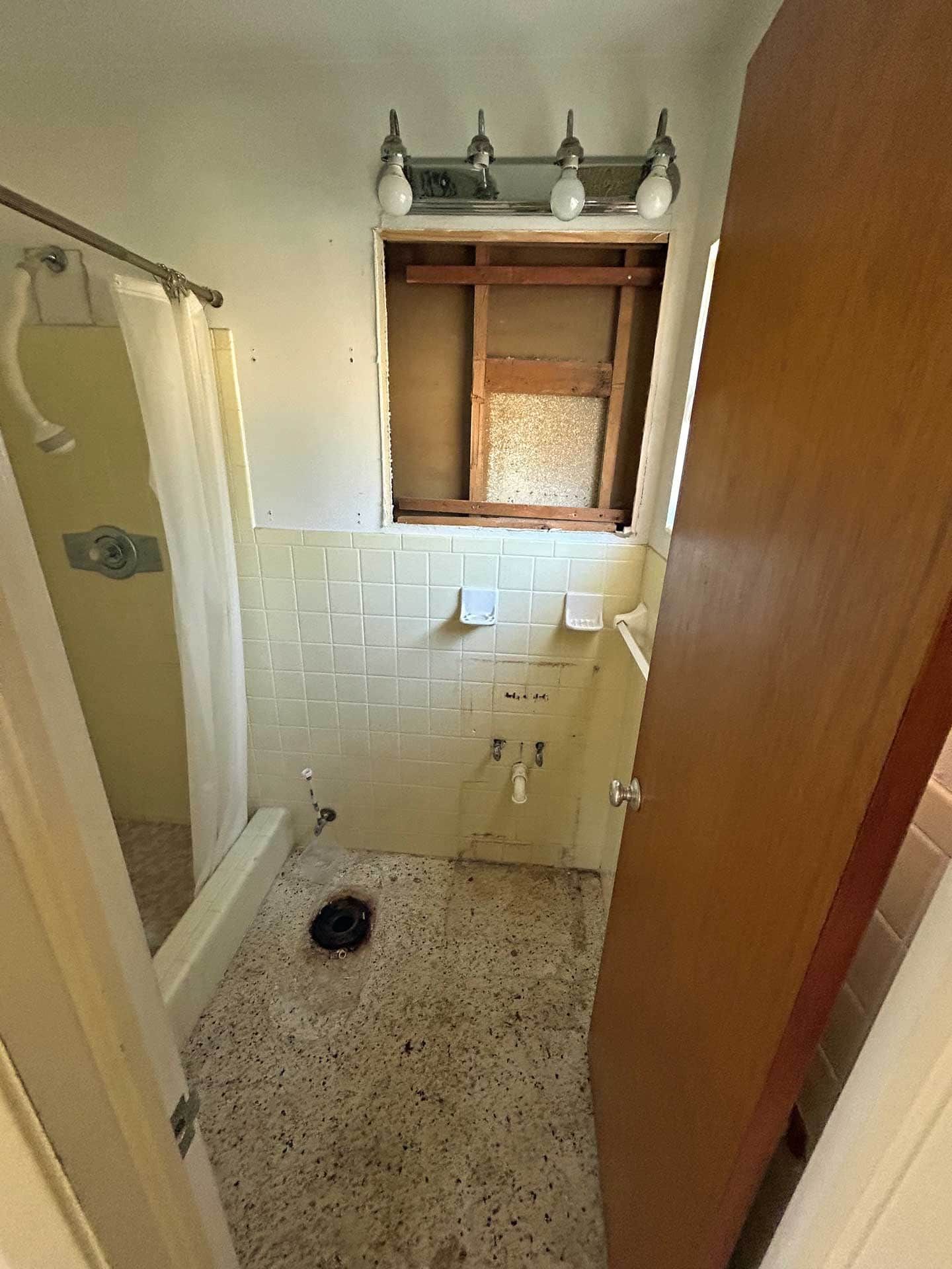 Bathroom with missing window and dated tile and fixtures.