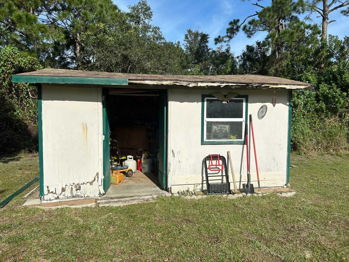 An old white shed with green trim before being removed.