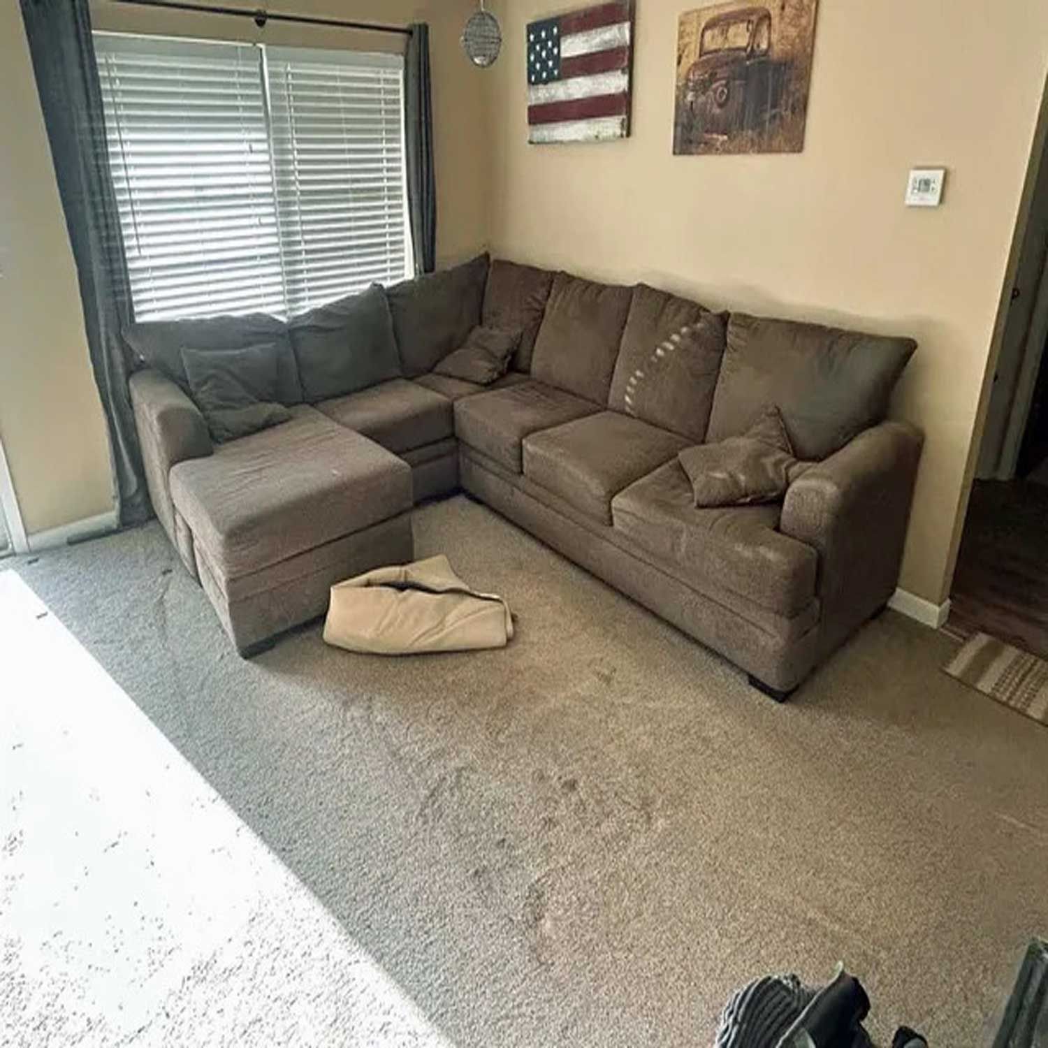 A living room with a sectional couch and ottoman.