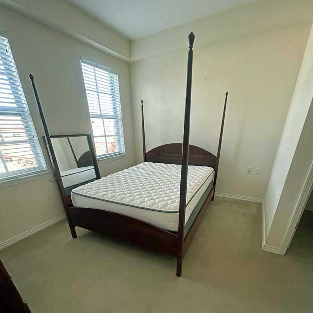 A bedroom with a four poster bed and a mirror.