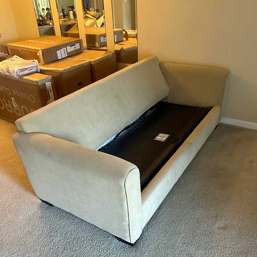 A couch is sitting in a room with boxes behind it.