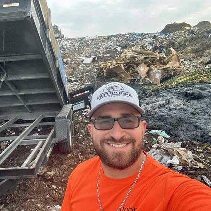 John Keefer taking a selfie in front of a dumpster at a dumpster.