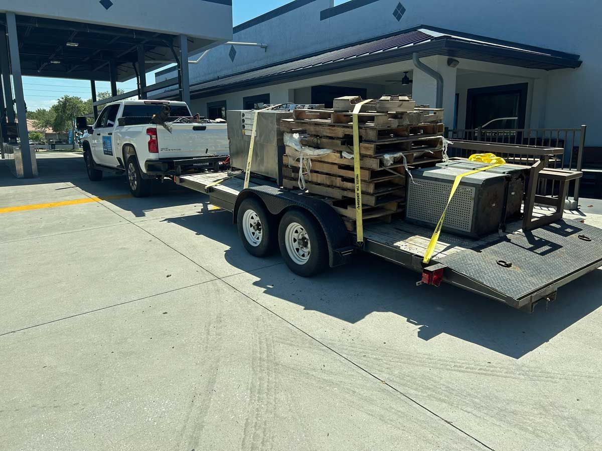 A white truck is pulling a trailer full of wooden pallets.