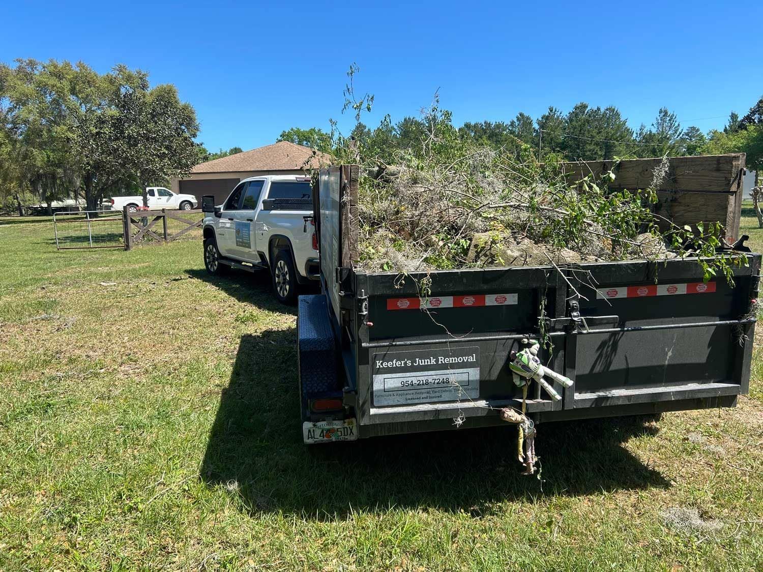 A Keefer's trailer is parked in a field next to a truck after a storm.