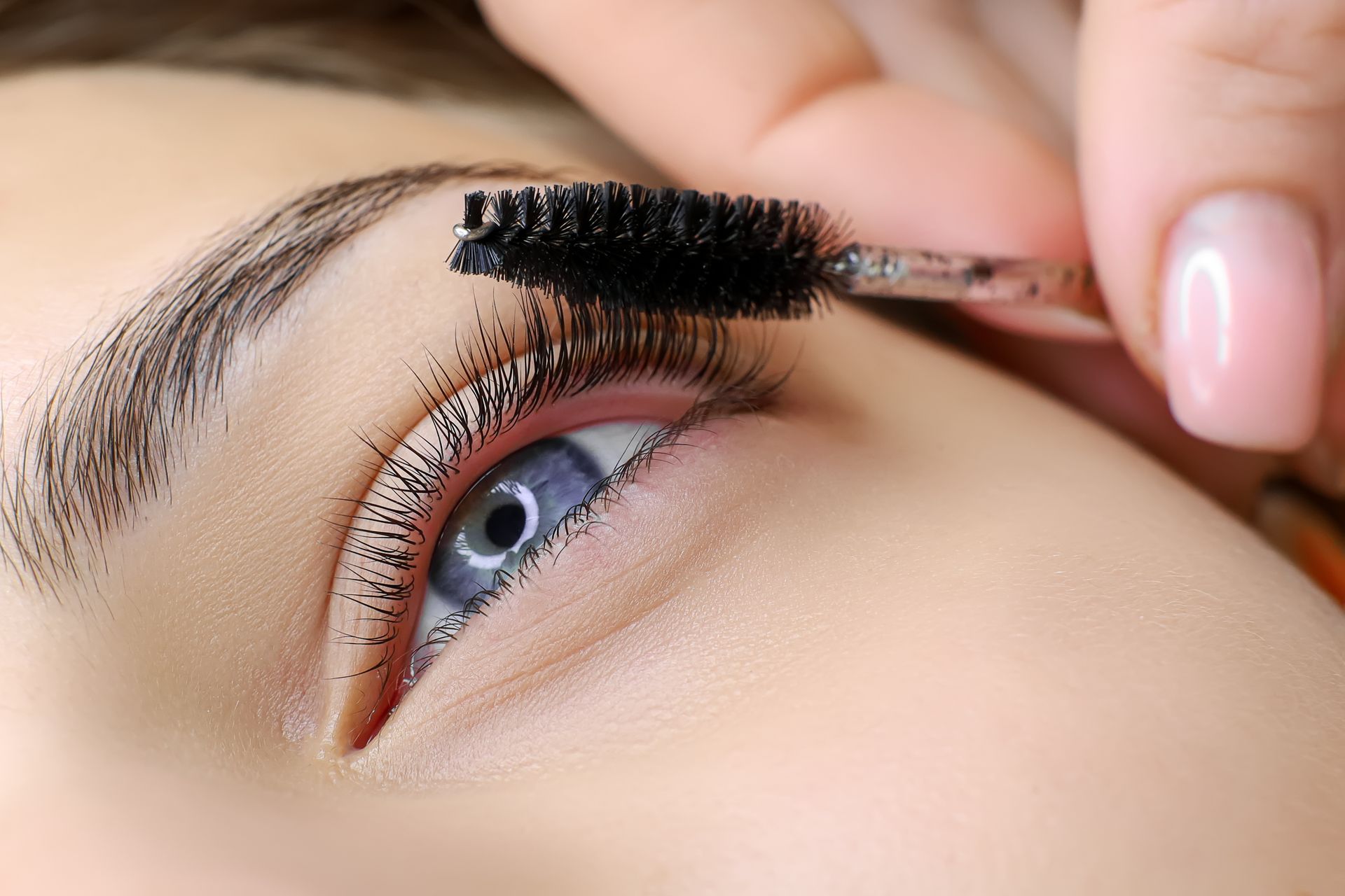 Eine Nahaufnahme einer Frau, die sich Wimperntusche auf die Augen aufträgt.