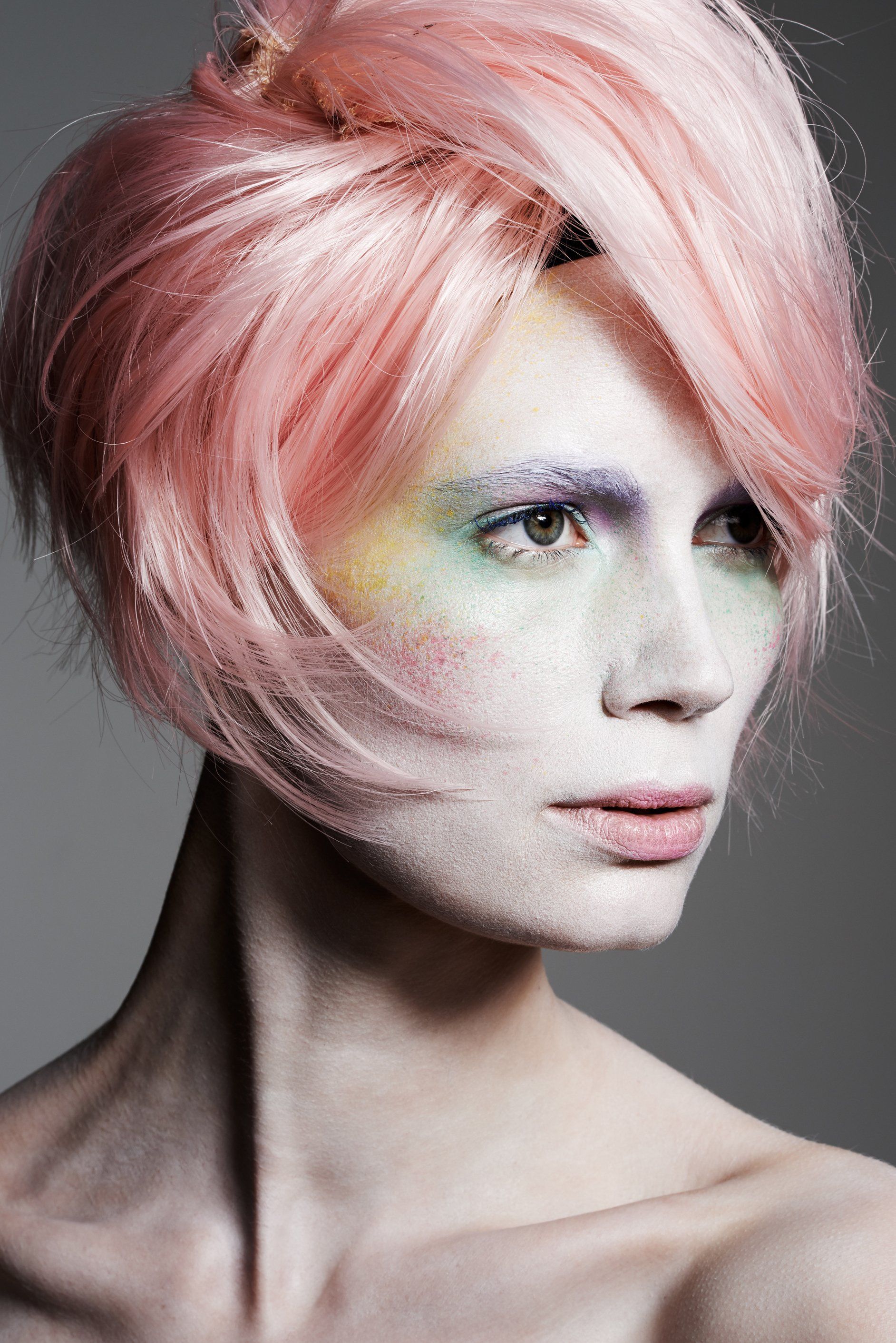 Eine Frau mit rosa Haaren und Regenbogen-Make-up im Gesicht.
