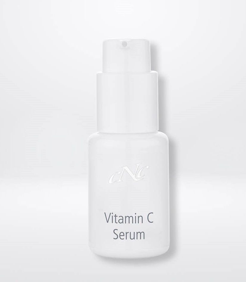Eine weiße Flasche Vitamin-C-Serum steht auf einer weißen Oberfläche.