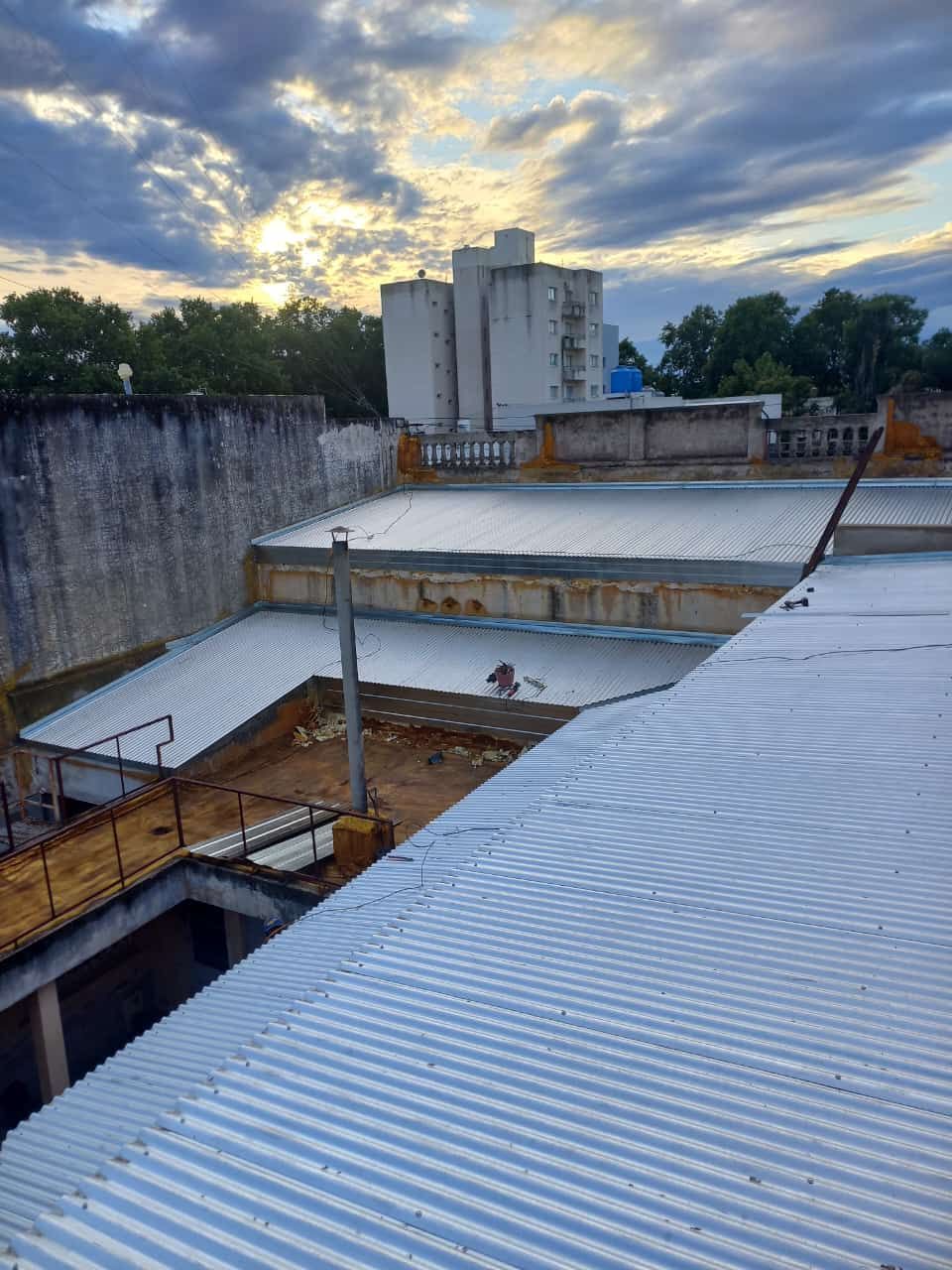 Azotea con techos de chapa ondulada y estructuras de hormigón al atardecer bajo un cielo nublado.