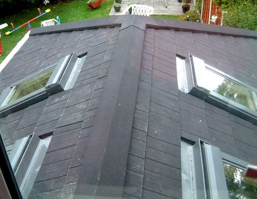 Dark tiled roof with four skylights, seen from an upper window. Green yard below.