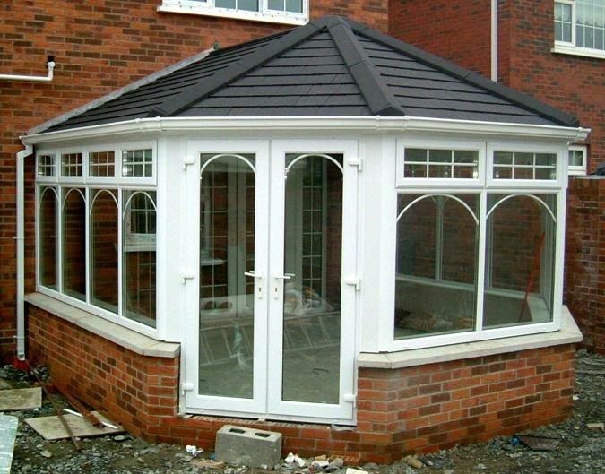 Brick conservatory with white window frames and a dark roof.