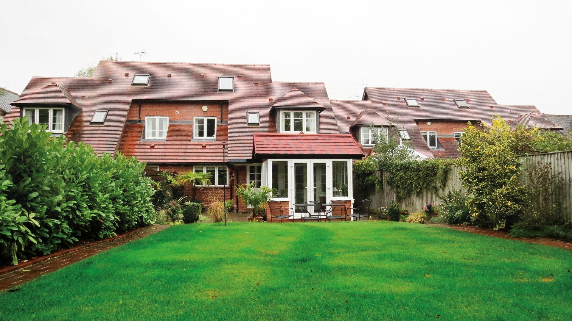 Red brick house with a large green lawn and garden.