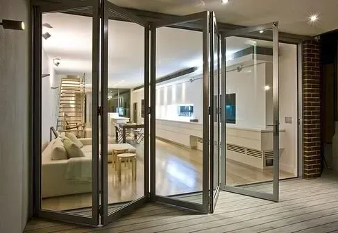 Folding glass doors open to a modern living space with white walls, furniture, and a view to an outdoor area with brick.