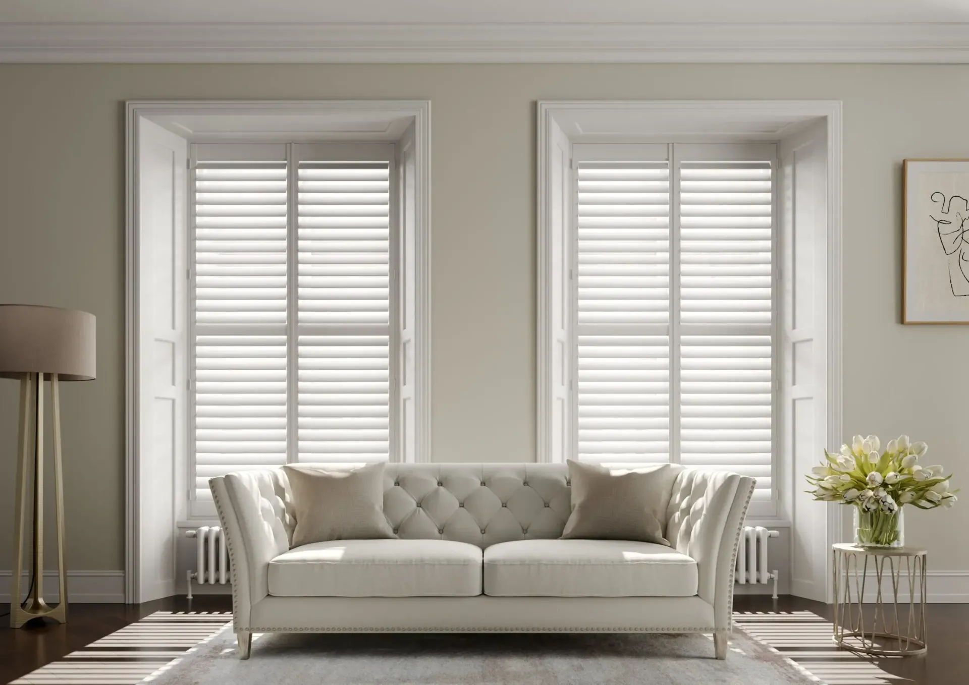 Living room with white shutters, a tufted sofa, and floral arrangement.
