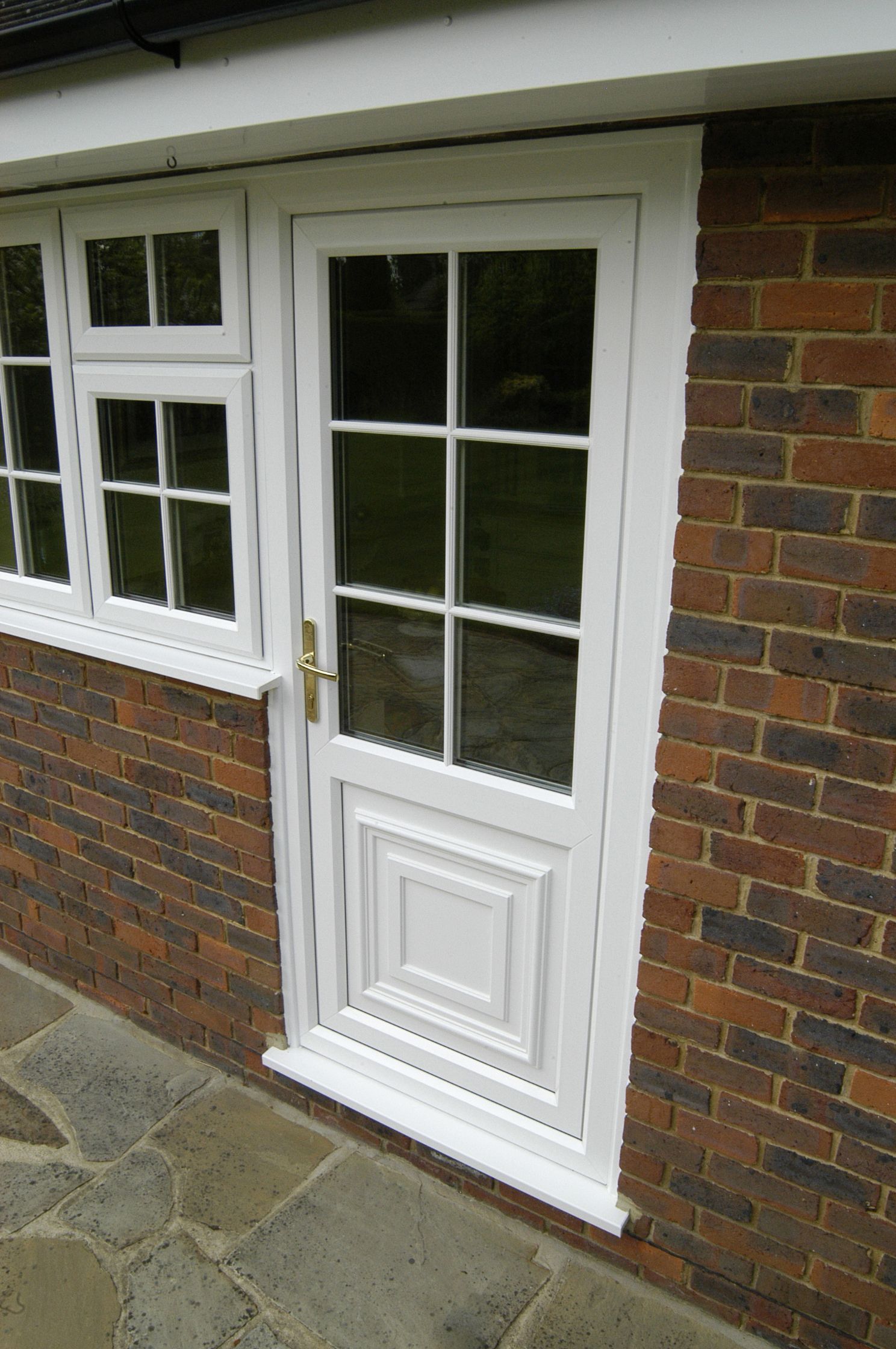 White paneled door with window, set in brick wall.