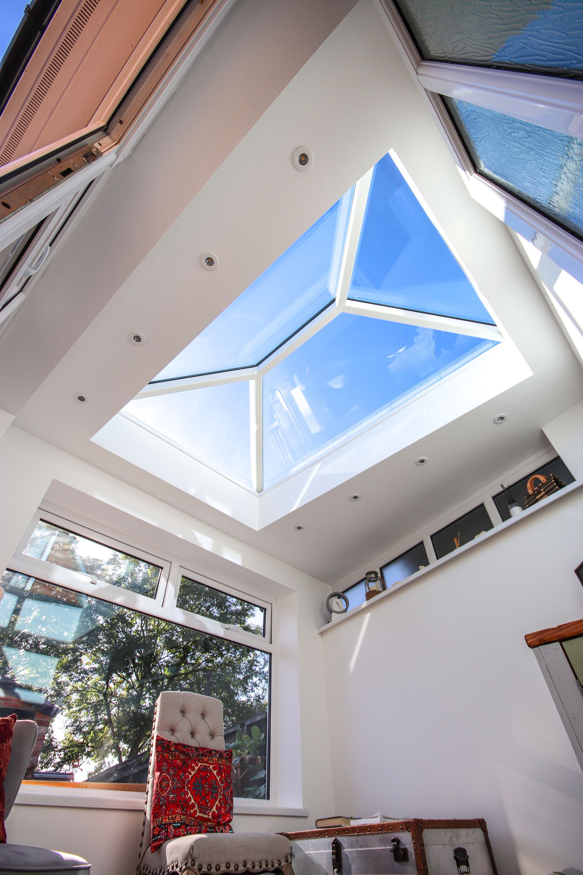 Sunroom interior with a large skylight, bright white walls, and a view of the sky.