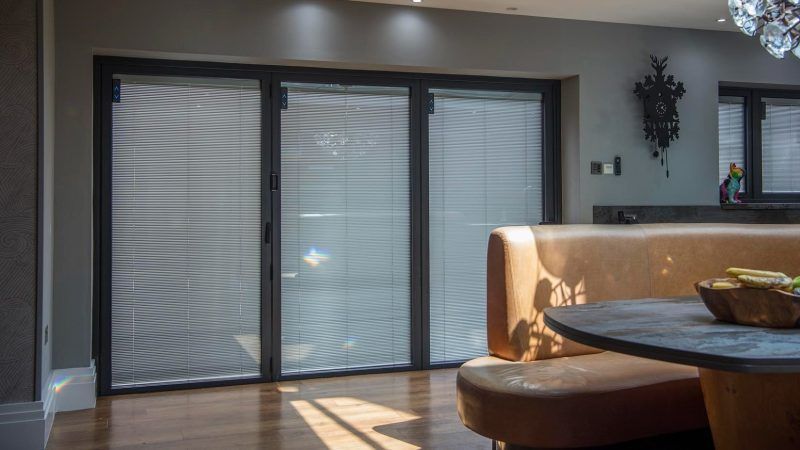 Brown leather booth at a round table; glass door with closed blinds.