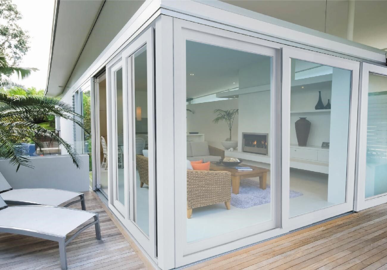 Patio with white framed glass doors overlooking a living room with furniture and a fireplace.
