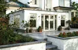 White house extension with patio, garden, and steps.