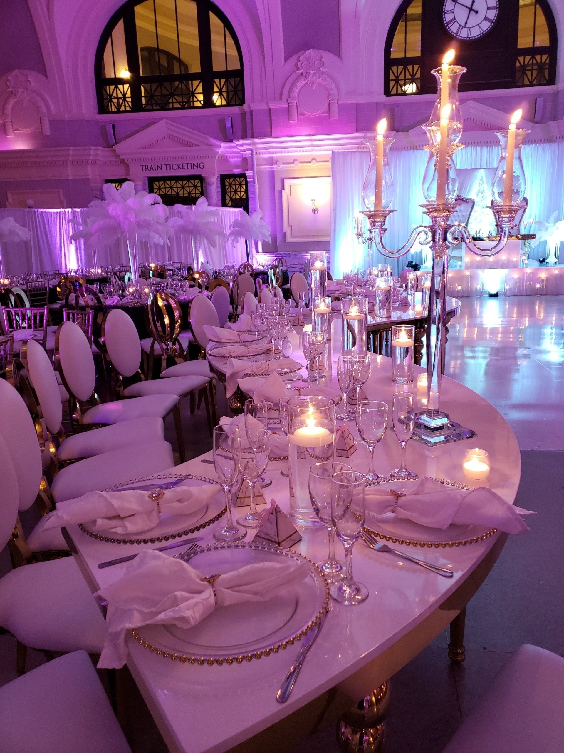 Lavender-lit banquet table set with crystal candelabras, china plates, and glassware in an elegant hall