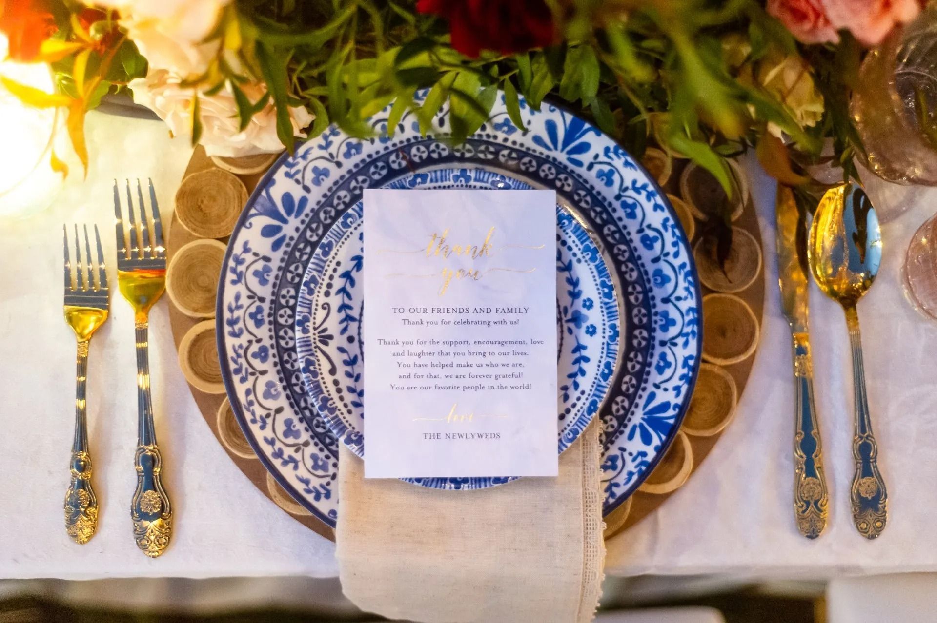 Elegant wedding table setting with blue-and-white china, gold flatware, and a floral centerpiece