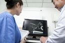 Two medical staff reviewing an X-ray on a monitor in a clinic room