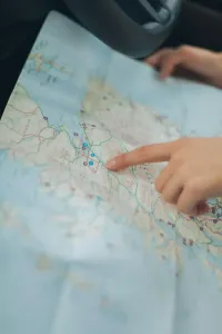 Hand pointing to a road map spread across a car seat