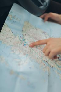Hand pointing to a road map spread across a car seat