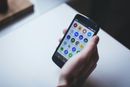 Hand holding a smartphone with a grid of colorful app icons on screen
