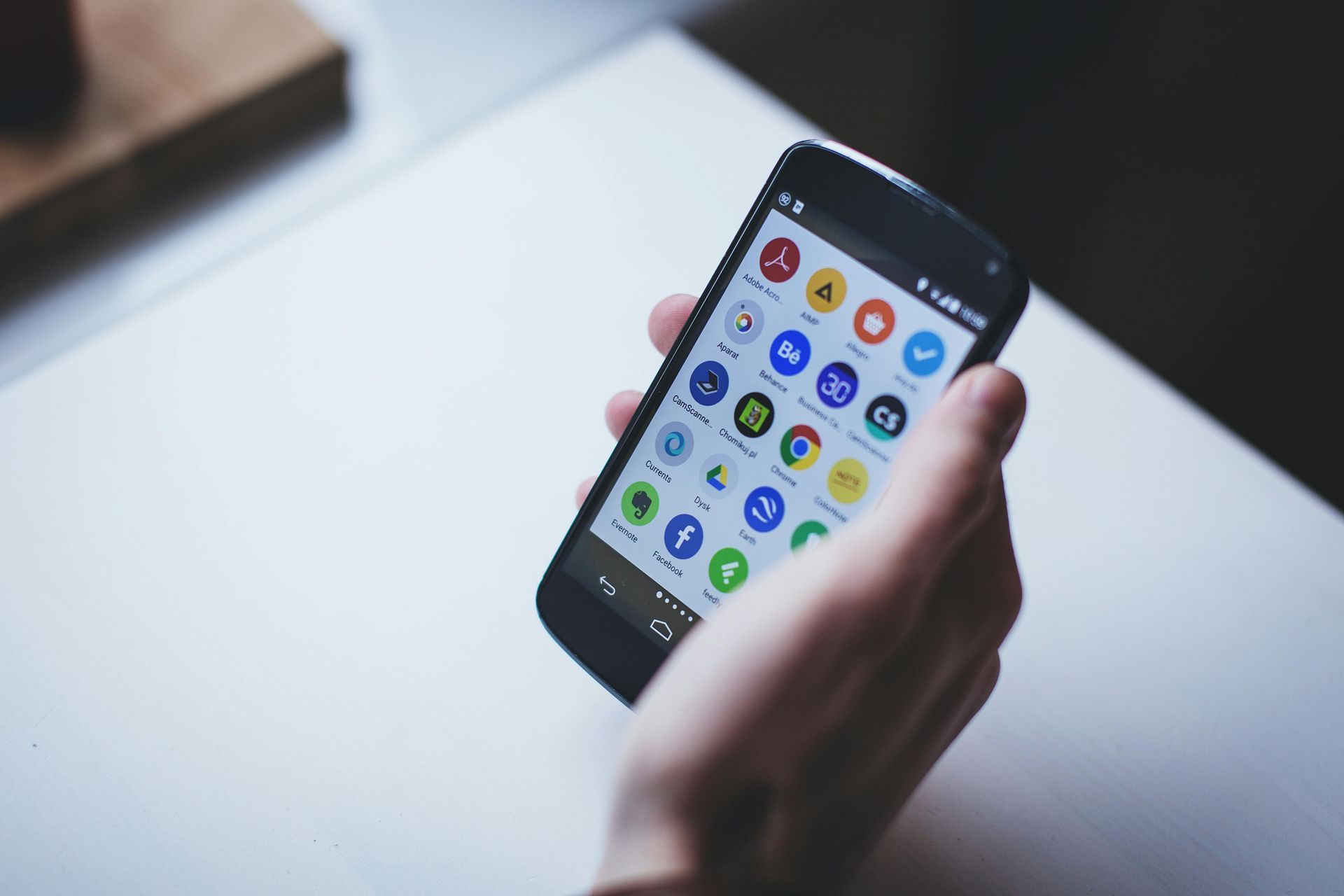 Hand holding a smartphone with a grid of colorful app icons on screen