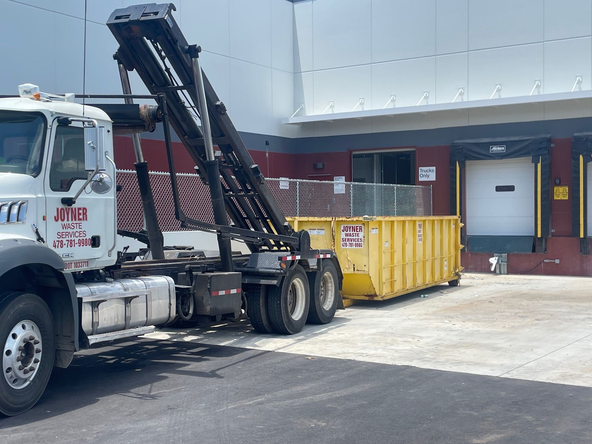 A blue dumpster is being loaded onto a dumpster trailer.