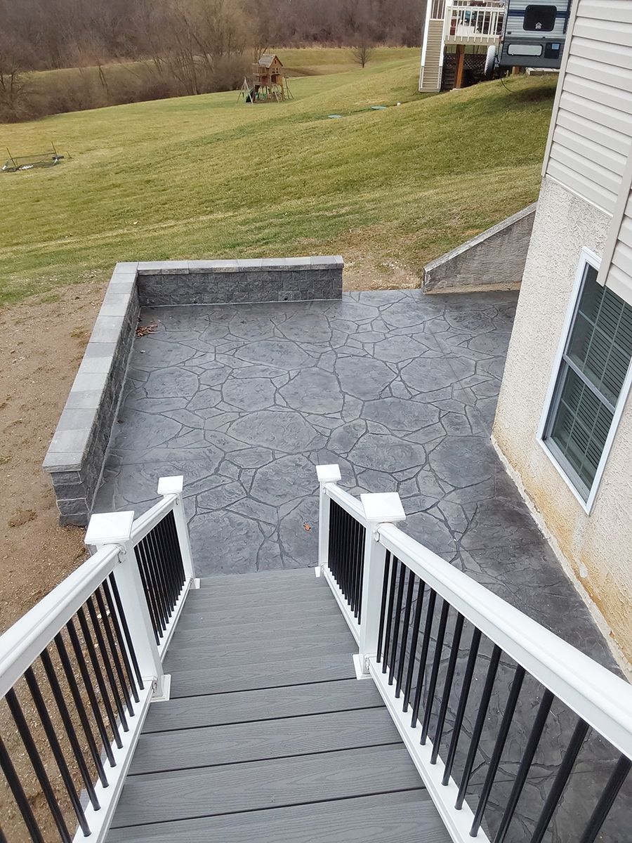A set of stairs leading up to a patio with a white railing.