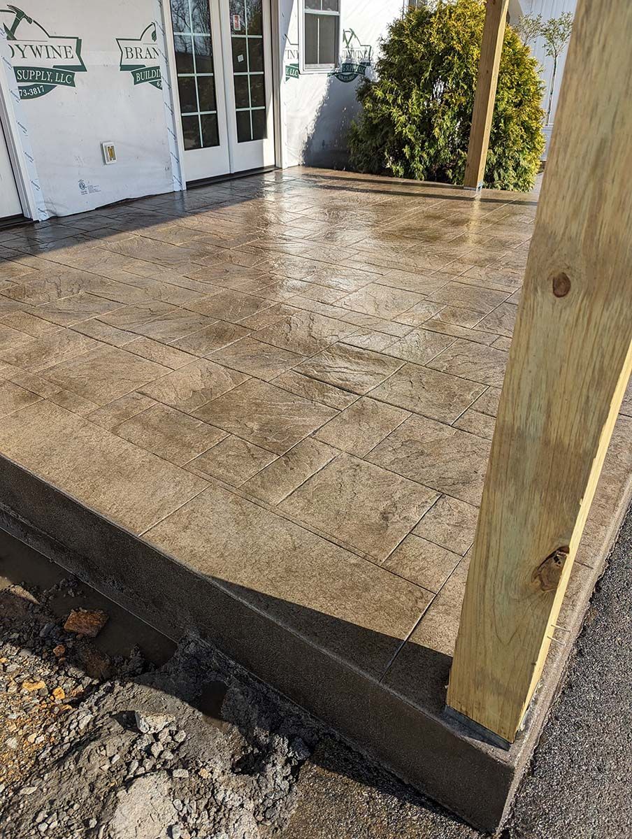 A concrete patio with a wooden post in front of a house.