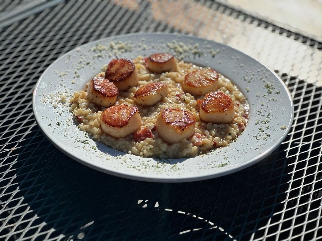 A plate of food with scallops and rice on a table.