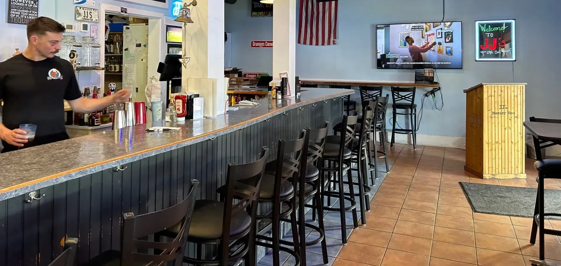 A man is standing behind a bar in a restaurant.
