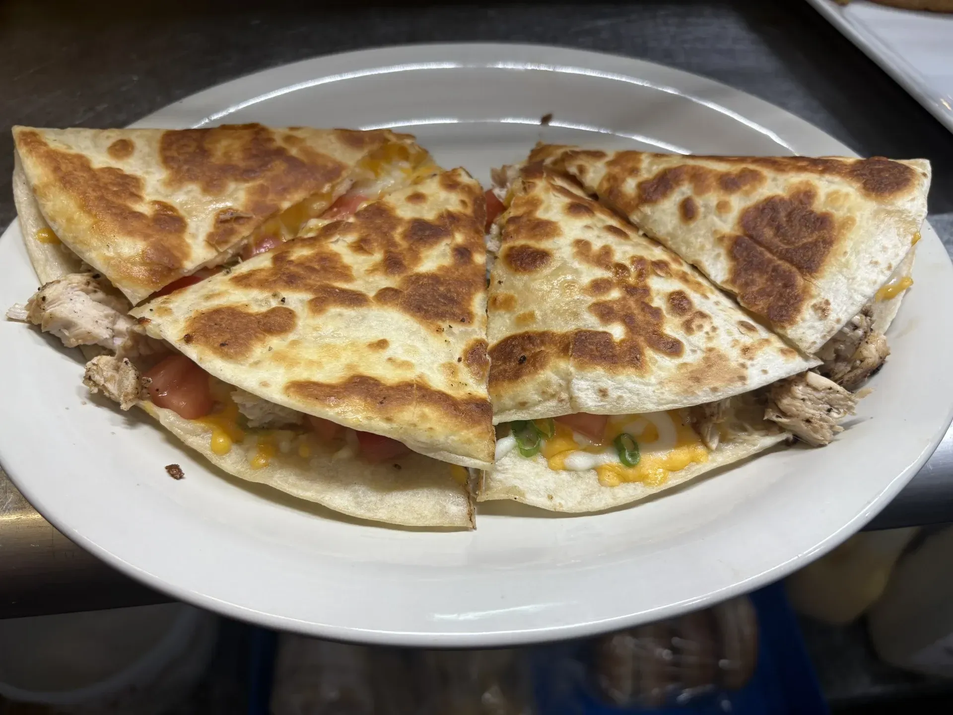 A white plate topped with a quesadilla with chicken and cheese.